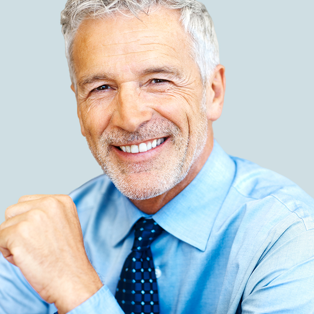 Smiling older man showing confidence with his false teeth dentures, highlighting natural-looking denture services.