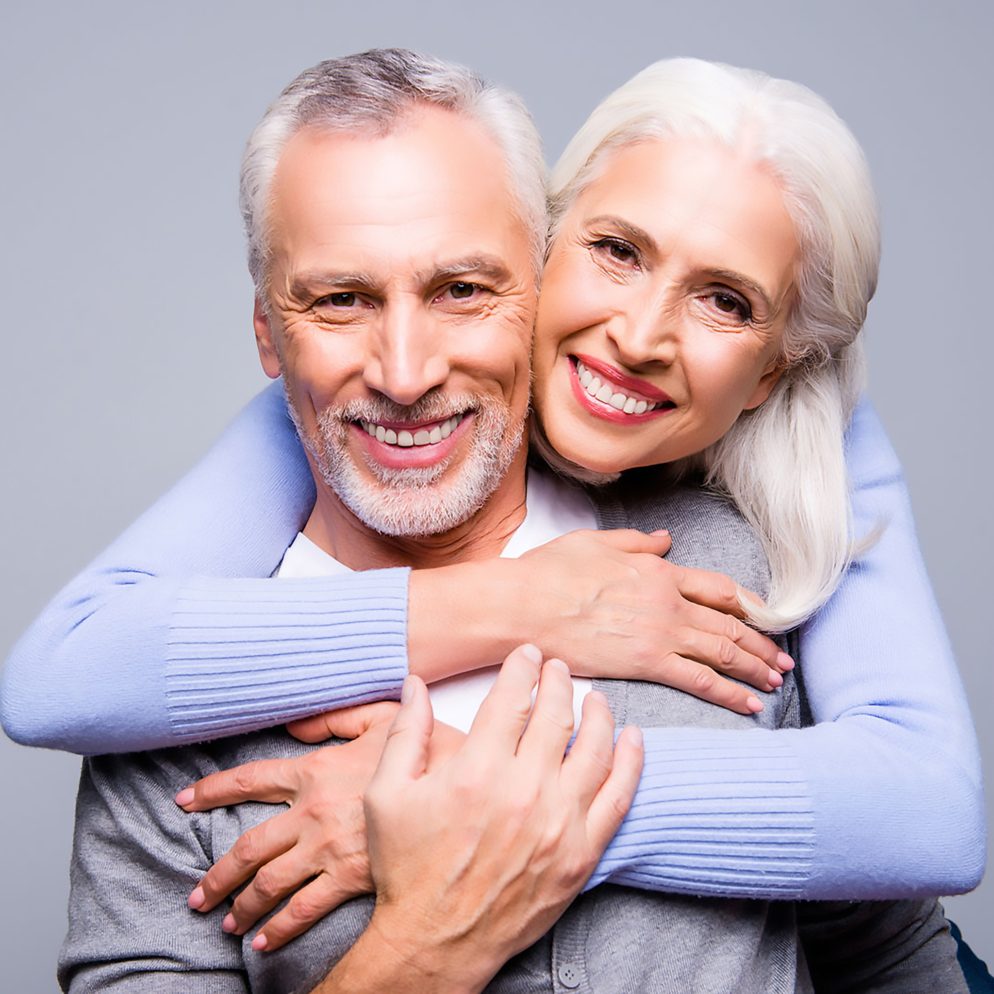 Happy couple embracing each other, smiling confidently while wearing dentures from Confidentures Auckland