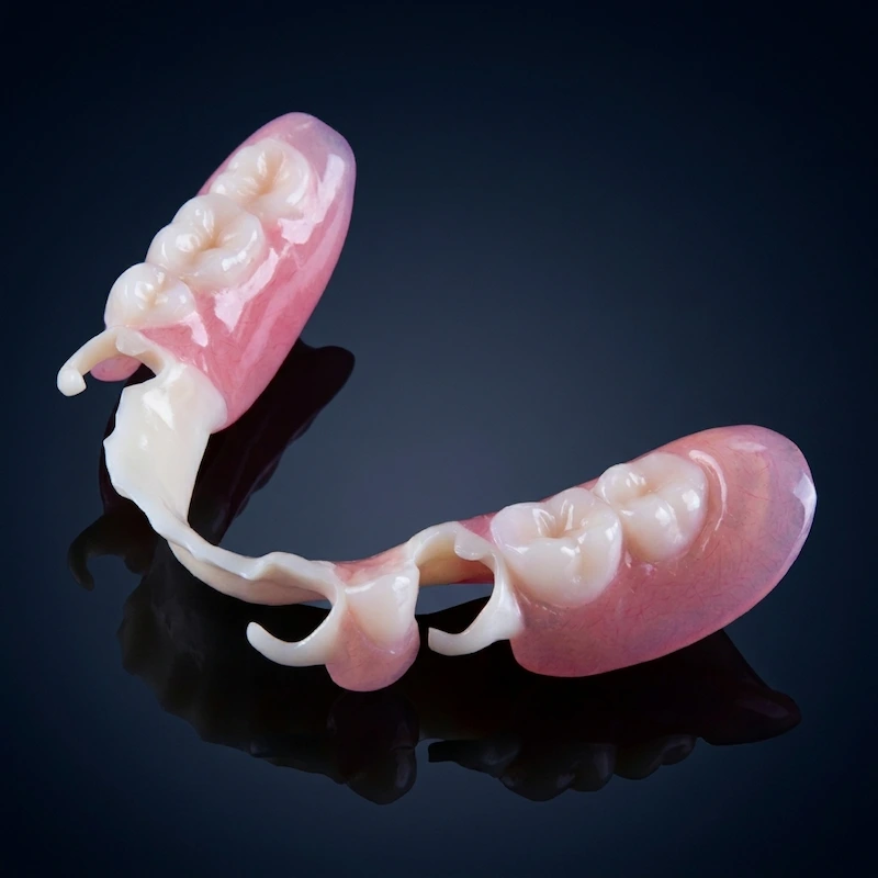 Extreme close-up of a flexible, thermoplastic partial denture clasp blending seamlessly with natural teeth for absolute visual discretion at Confidentures.
