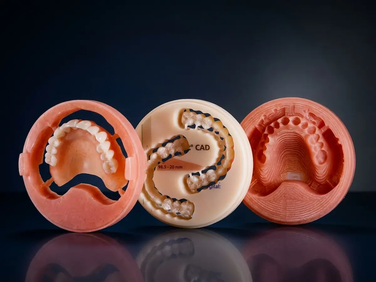 Three precision-milled PMMA denture pucks demonstrating the zero-shrinkage CAD/CAM technology used in our SEMCD Comfort Protocol to create friction-free, suction-fit prosthetics in Auckland.